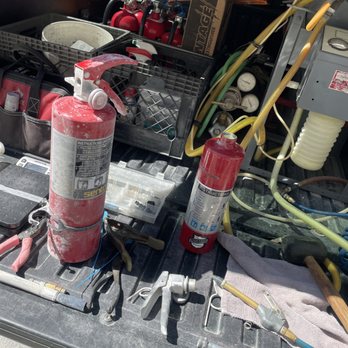 A worn fire extinguisher next to a freshly serviced unit