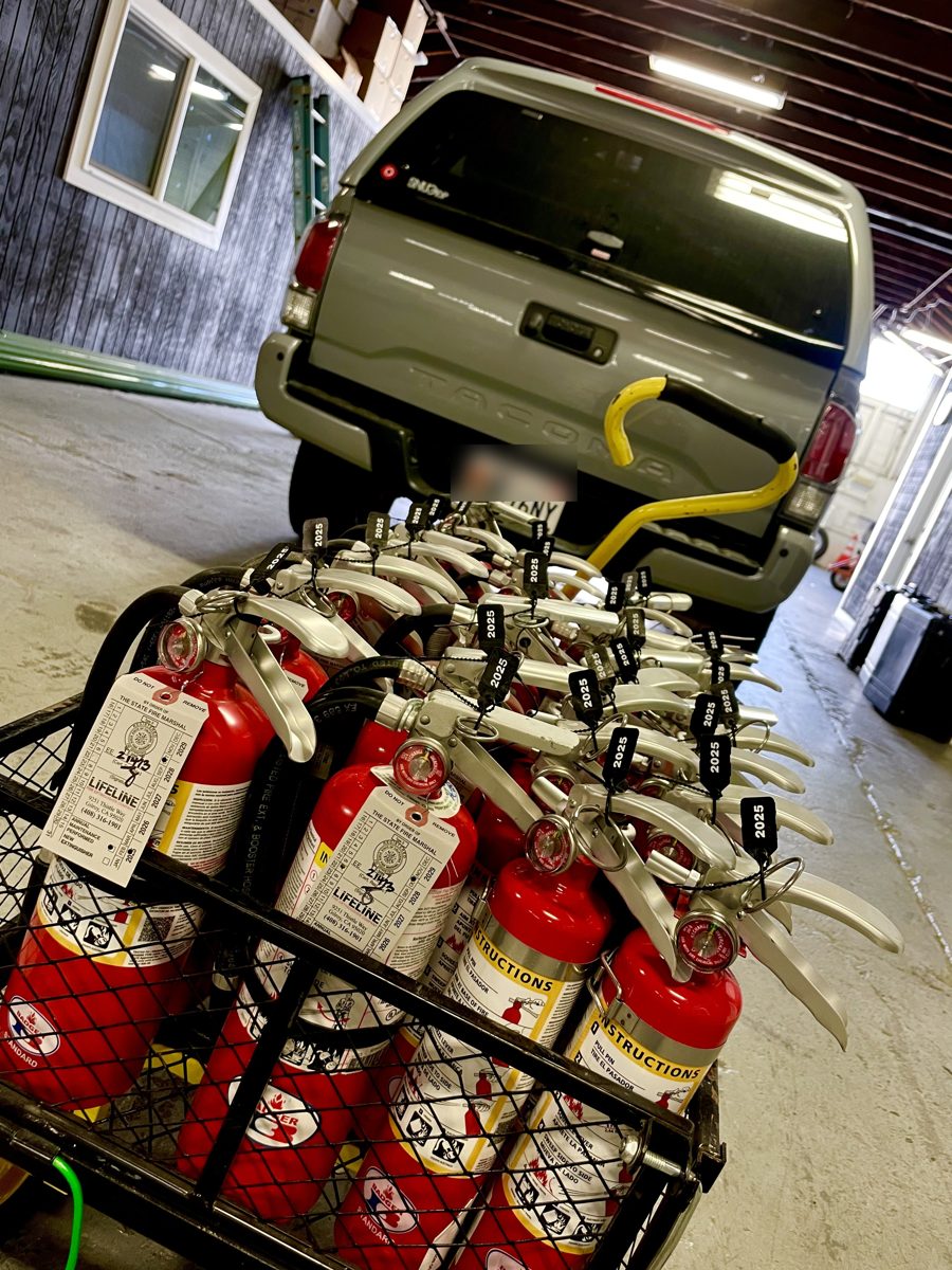 Cart of freshly serviced fire extinguishers with new state tags, loaded to go out on the truck